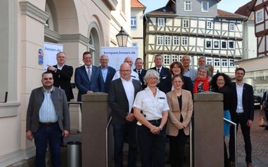 Viele Personen stehen am Eingang des Bürgerbüros zur Verleihung des "Kompass"-Siegels. Im Hintergrund stehen Banner mit der Aufschrift "kompass.hessen.de"