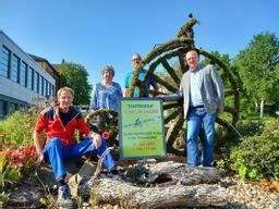 4 Personen die an einem großen, mit Moos bedeckten Fahrrad stehen. Davor eine Infotafel zum Stadtradeln.