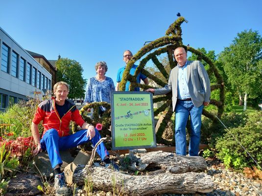 4 Personen die an einem großen, mit Moos bedeckten Fahrrad stehen. Davor eine Infotafel zum Stadtradeln.