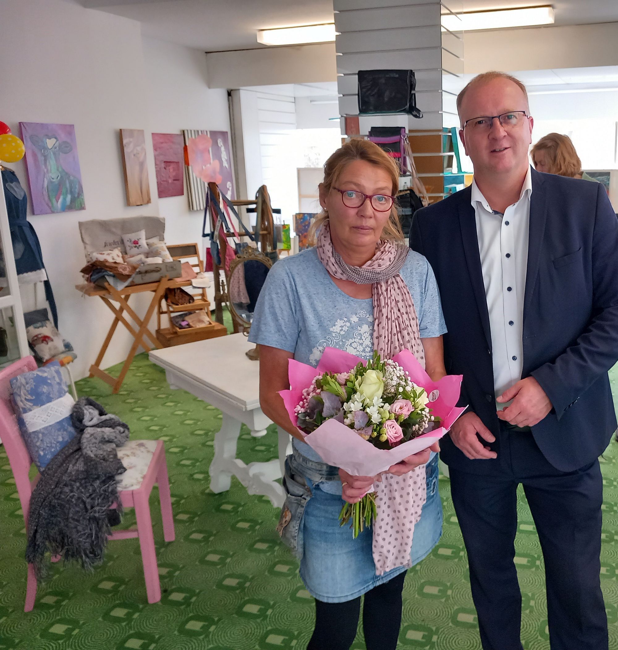 Der Bürgermeister neben einer Frau die Blumen hält im PopUp Store