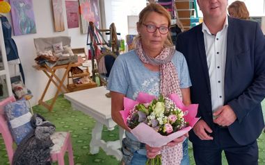 Der Bürgermeister neben einer Frau die Blumen hält im PopUp Store