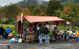 Eine Gruppe von Personen und Kindergartenkinder die an einem Säfte-Stand stehen