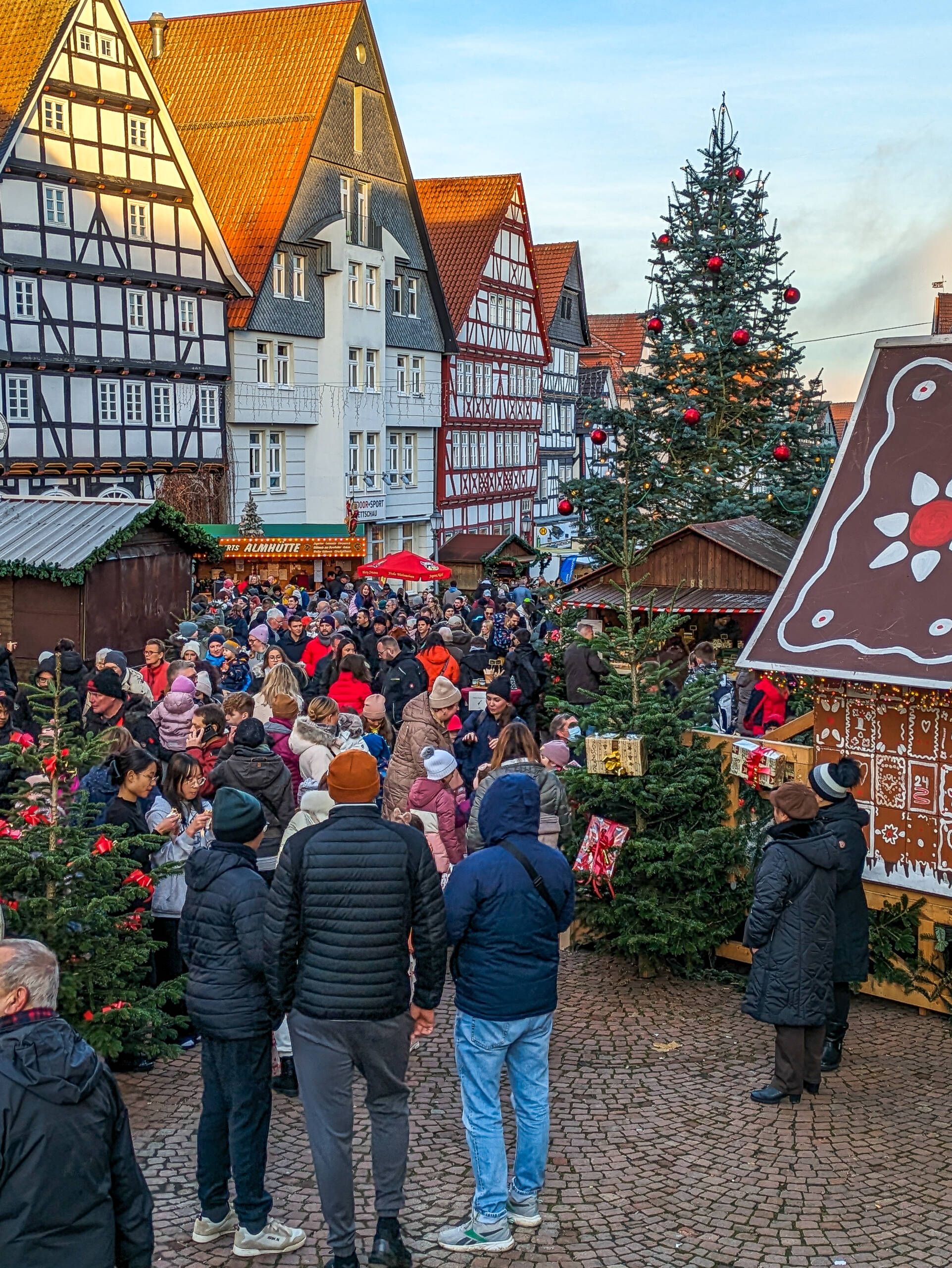 Zu sehen sind Menschen vor Ständen auf derm Weihnachtsmarkt in Bad Wildungen. Im Hintergrund sind Fachwerkhäuser zu sehen.