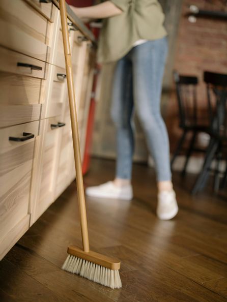 Ein Holzbesen, der an einem Unterschrank angelehnt ist.