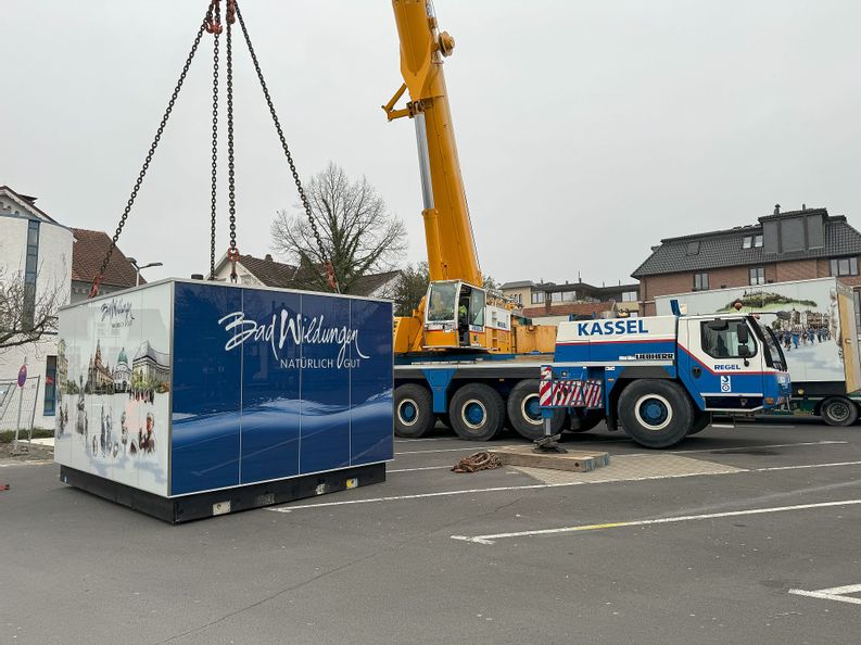 Ein Kran lässt ein Toilettenhaus auf einem Parkplatz der Brunnenallee ab