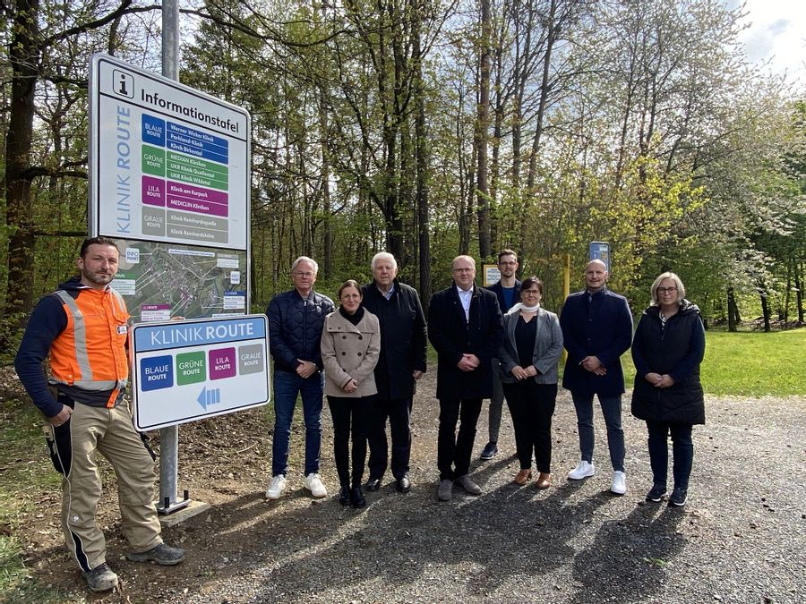 9 Personen stehen neben einer Infotafel und Ausschilderung von Reinhardshausen