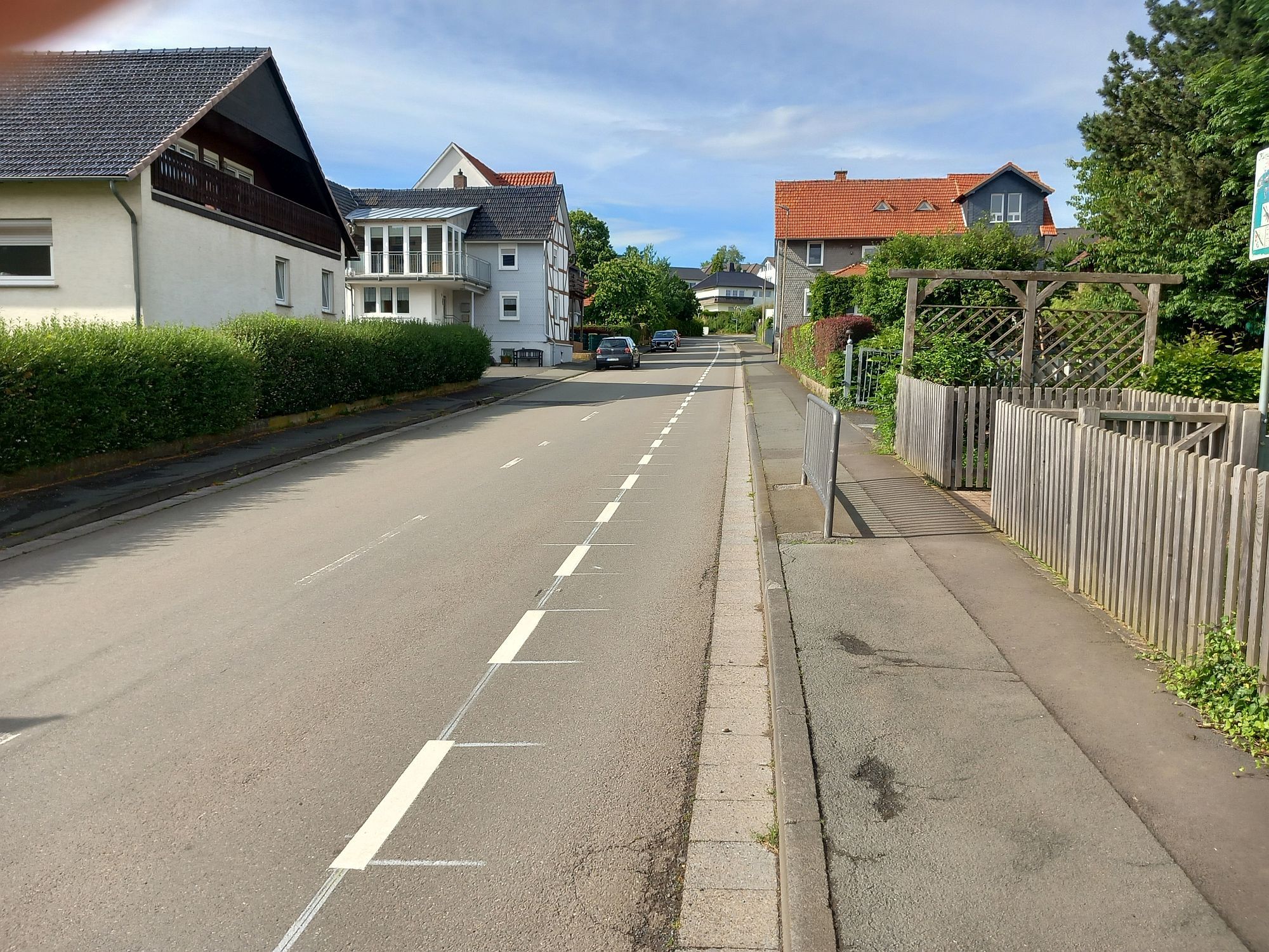 Blick auf die Anraffer Straße, welche von Wohnhäusern und einem Spielplatz umgeben ist.