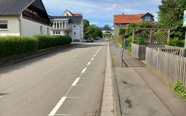Blick auf die Anraffer Straße, welche von Wohnhäusern und einem Spielplatz umgeben ist.