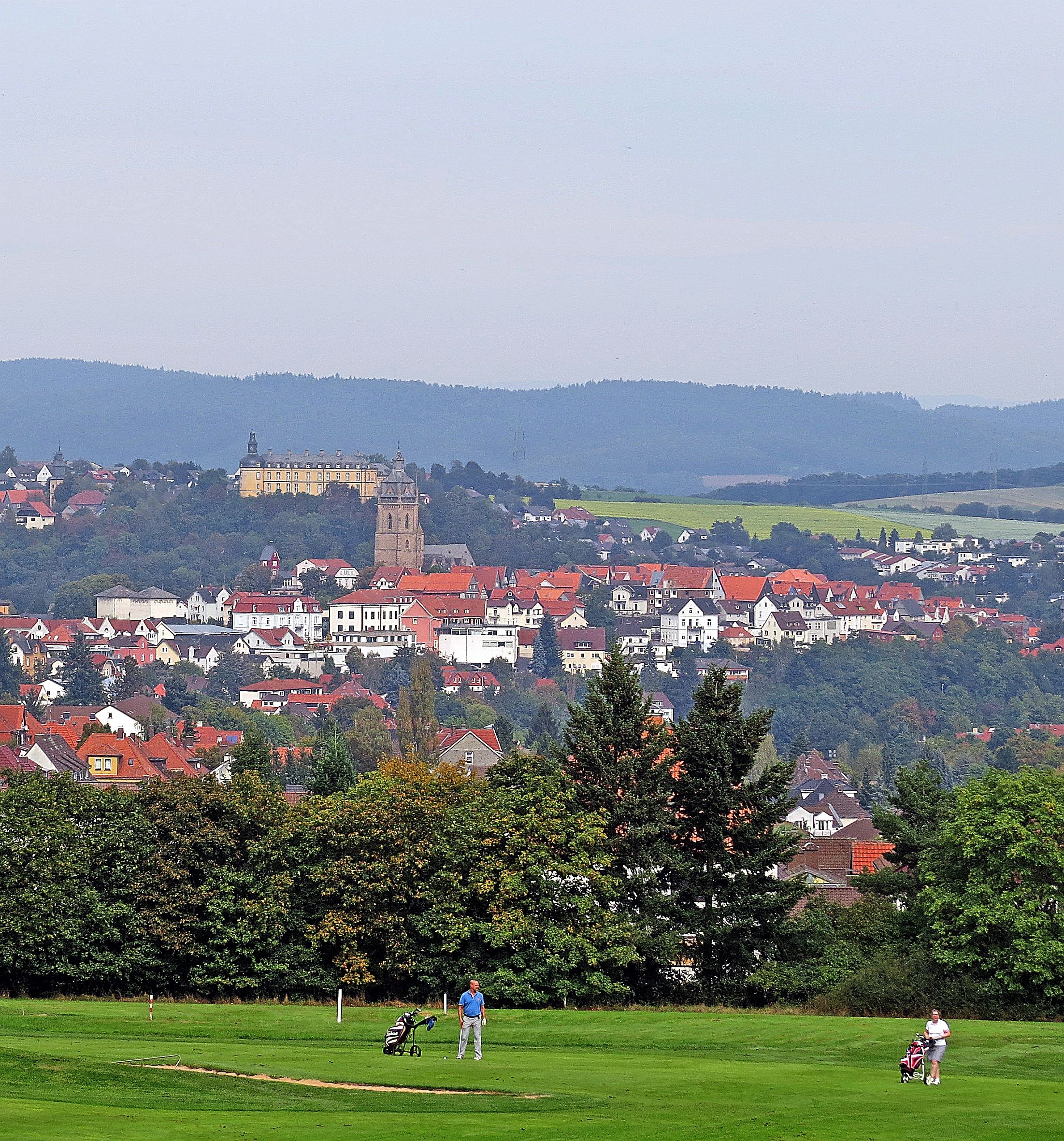 Blick aus der Ferne auf eine Golfanlage. Im Hintergrund lässt sich die Bad Wildunger Altstadt sehen.