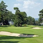 Blick auf eine Golfanlage, die mit Bäumen und Sandbunkern bedeckt ist.