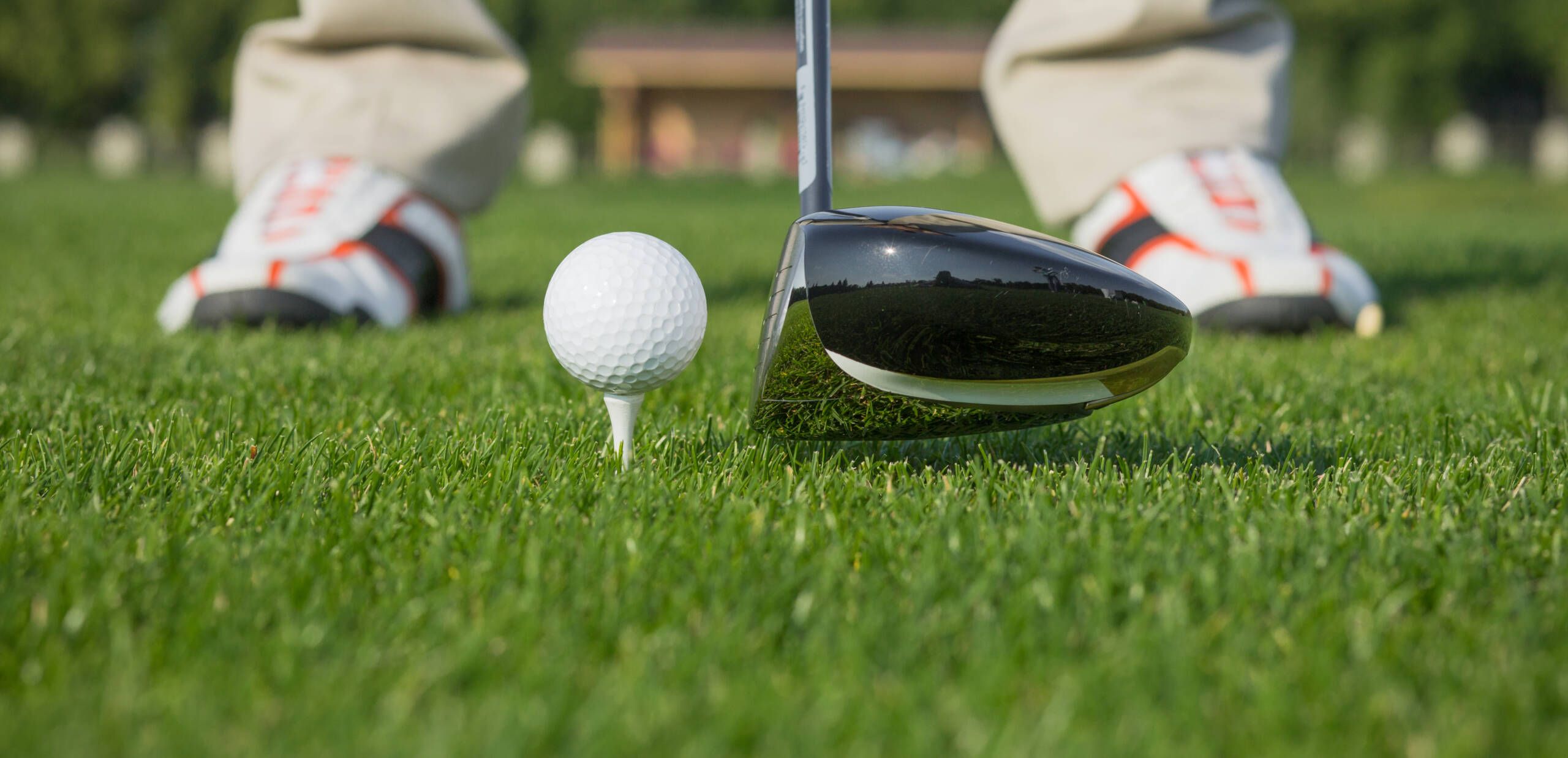 Nahaufnahme von einem Golfschläger, der ein paar Centimeter vor einem Golfball gehalten wird