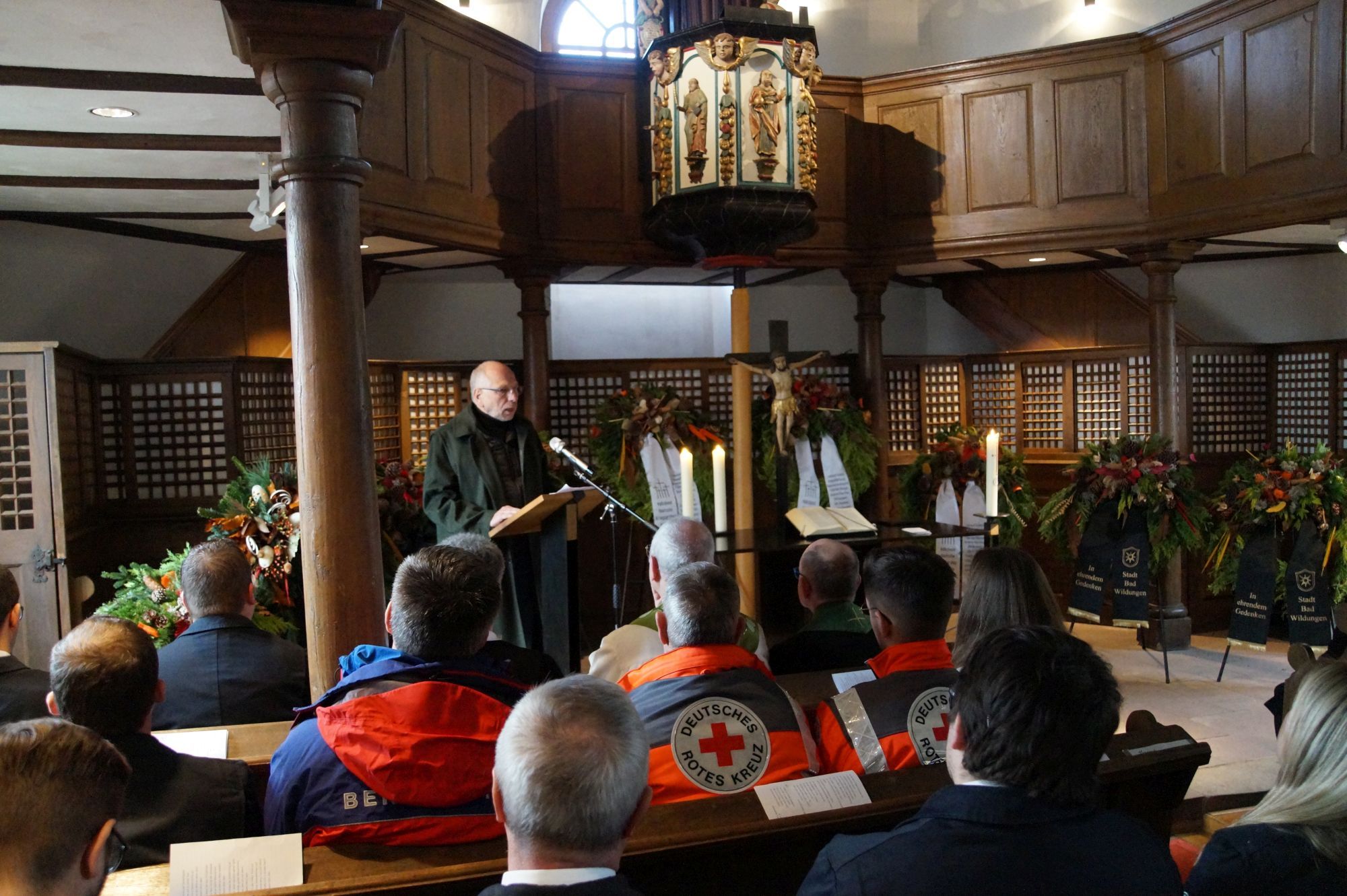 Ein Mann hält vor vielen Personen eine Rede in der Philipp-Nicolai Kirche. Um den Alter herum sind Gedenk-Kränze aufgebaut.