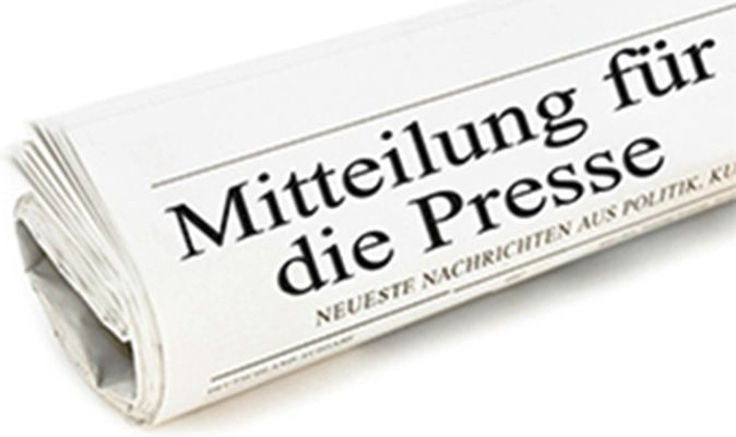 Eine zusammengerollte Zeitung auf weißem Boden. In großen Buchstaben steht "Mitteilung für die Presse" im Titel.