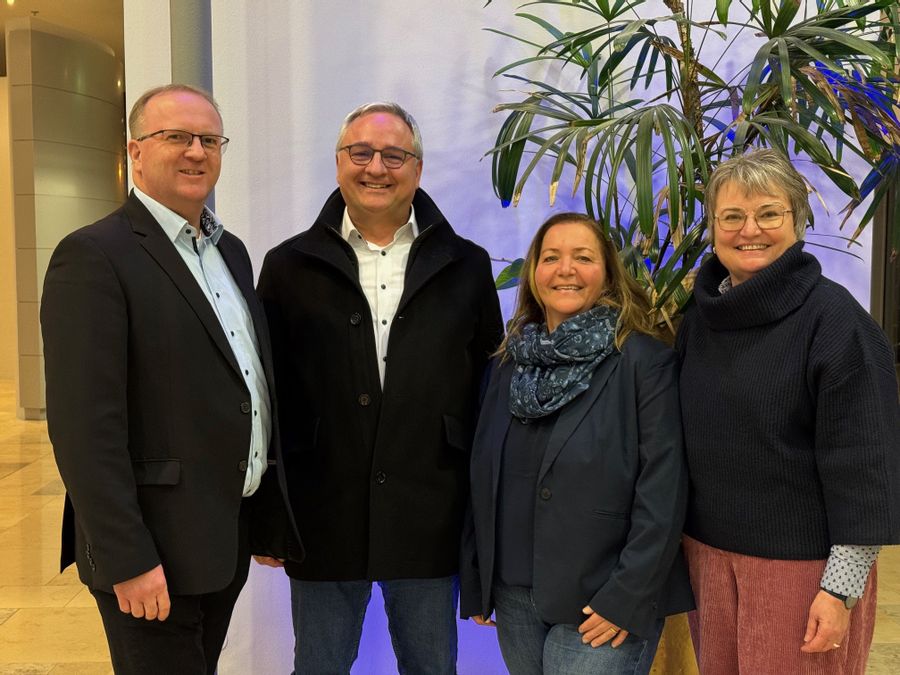 4 Personen stehen in de Wandelhalle und blicken in die Kamera