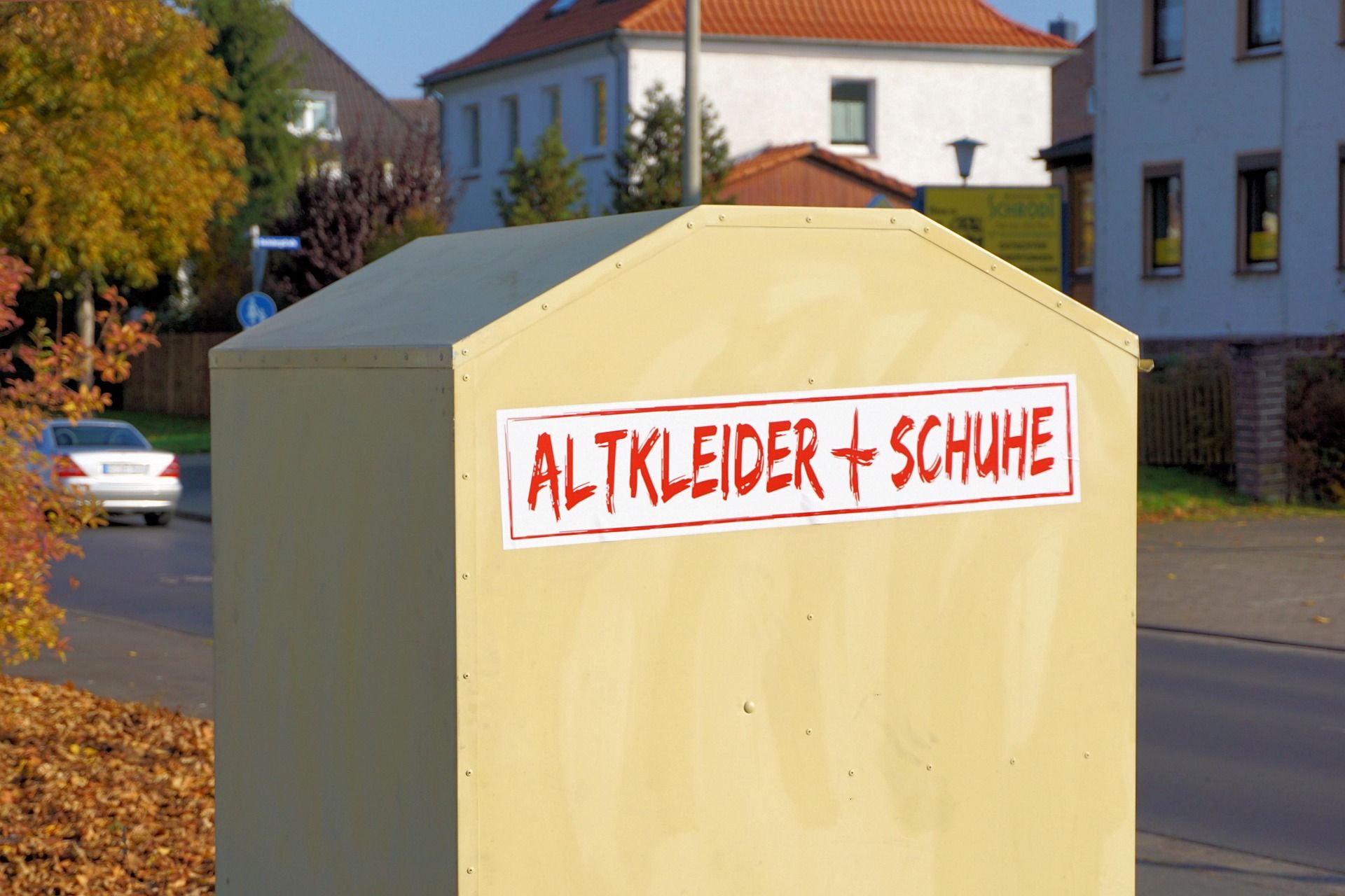 Ein Altkleidercontainer mit der Aufschrift Altkleider + Schuhe, der an einer Straße steht.