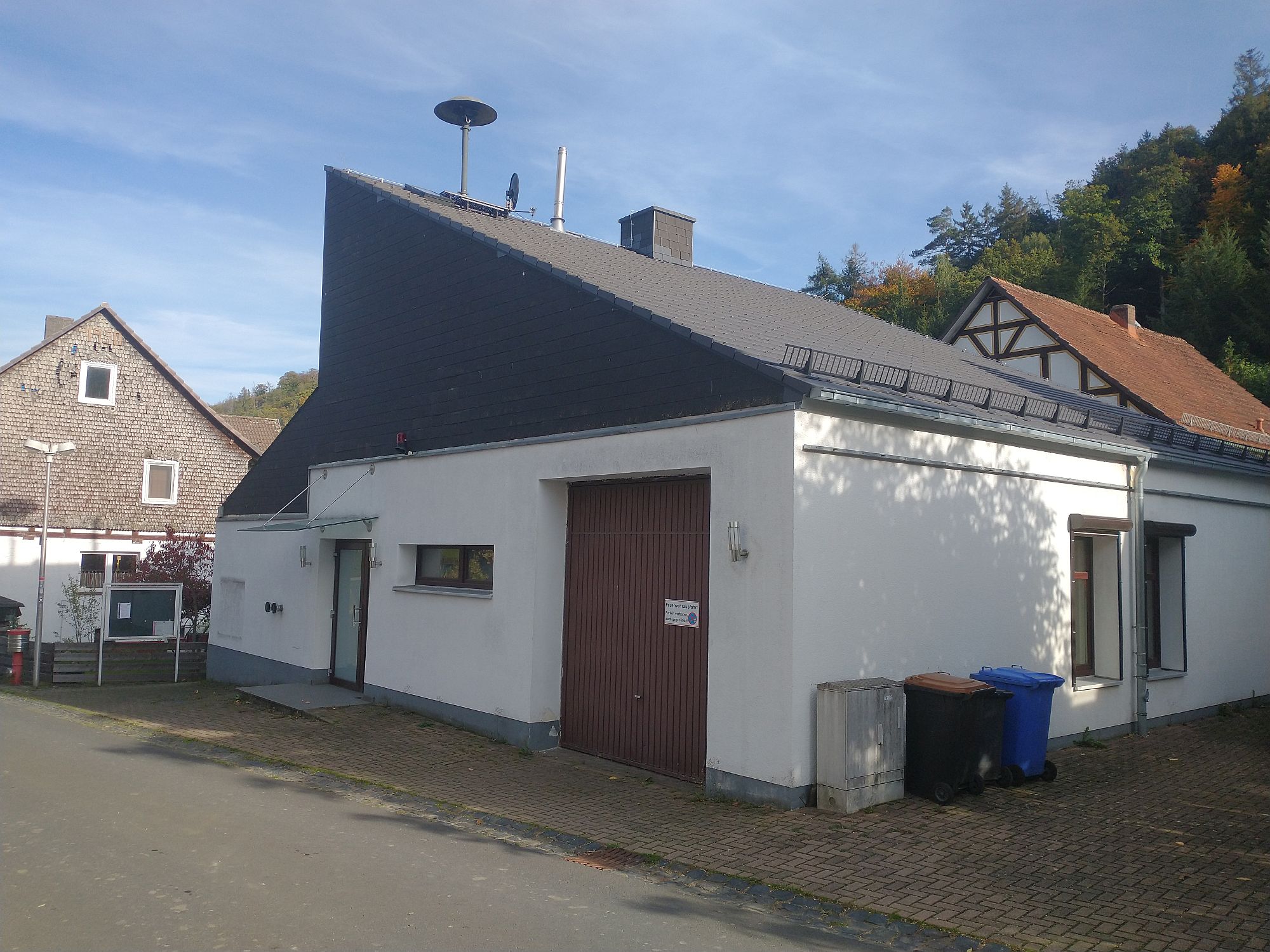 Außenaufnahme des Dorfgemeinschaft Haus Hüddingen. Zu sehen ist die Eingangstür und ein Garagentor.