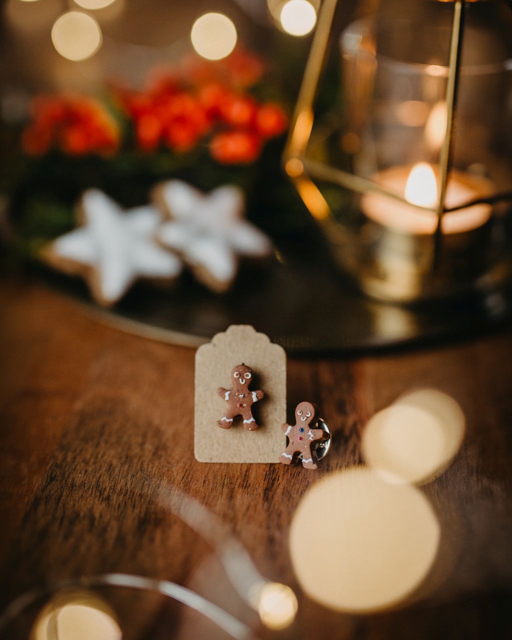 Zu sehen sind eine Laterne mit einer Kerze sowie zwei kleine Lebkuchenmännchen und Zimtsterne auf einem Tisch.