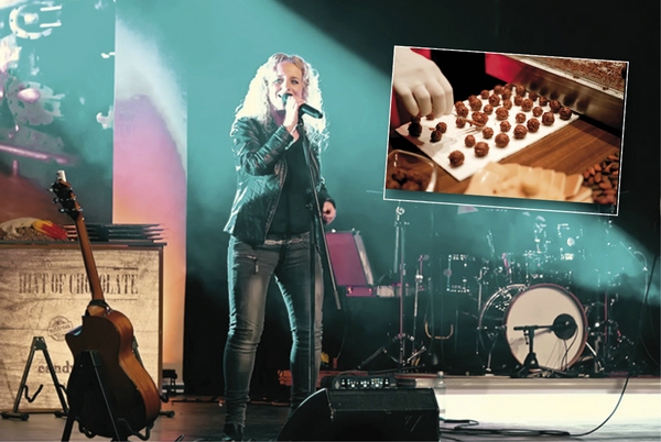 Zu sehen ist die Sängerin Christina Rommel auf der Bühne. Im Hintergrund sieht man ein Schlagzeug und vorne links eine Gitarre. Oben rechts ist ein kleines Bild eingefügt, auf dem Pralinen zu sehen sind, die gerade gemacht werden.