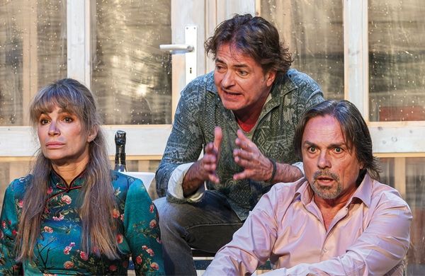 Zu sehen sind eine Frau und zwei Männer, die sitzen und aufgebracht wirken.