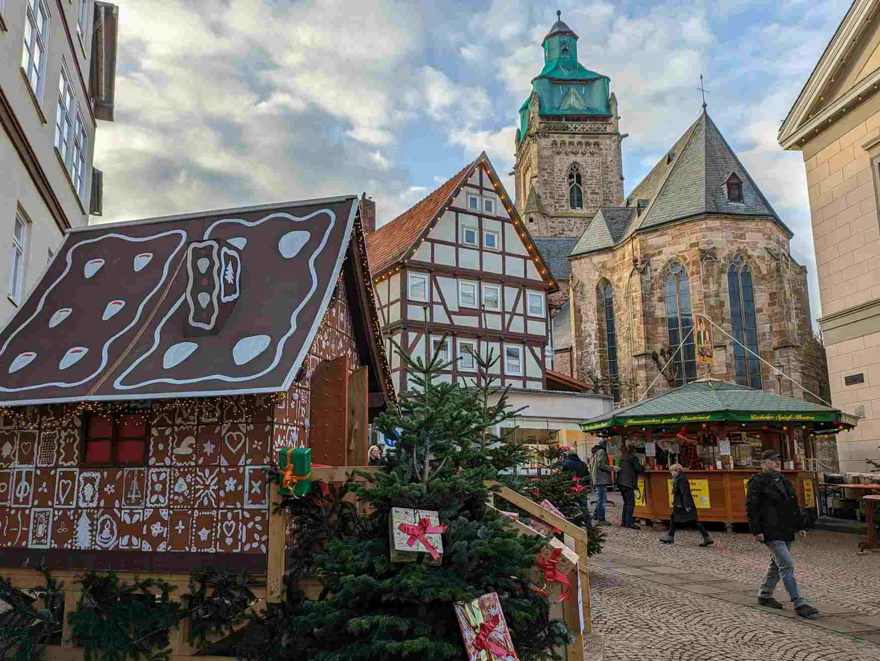 Zu sehen ist das Lebkuchenhaus auf dem Weihnachtsmarkt in Bad Wildungen am Tage. Im Hintergrund ist ein Fachwerkhaus sowie die Stadtkirche zu sehen.