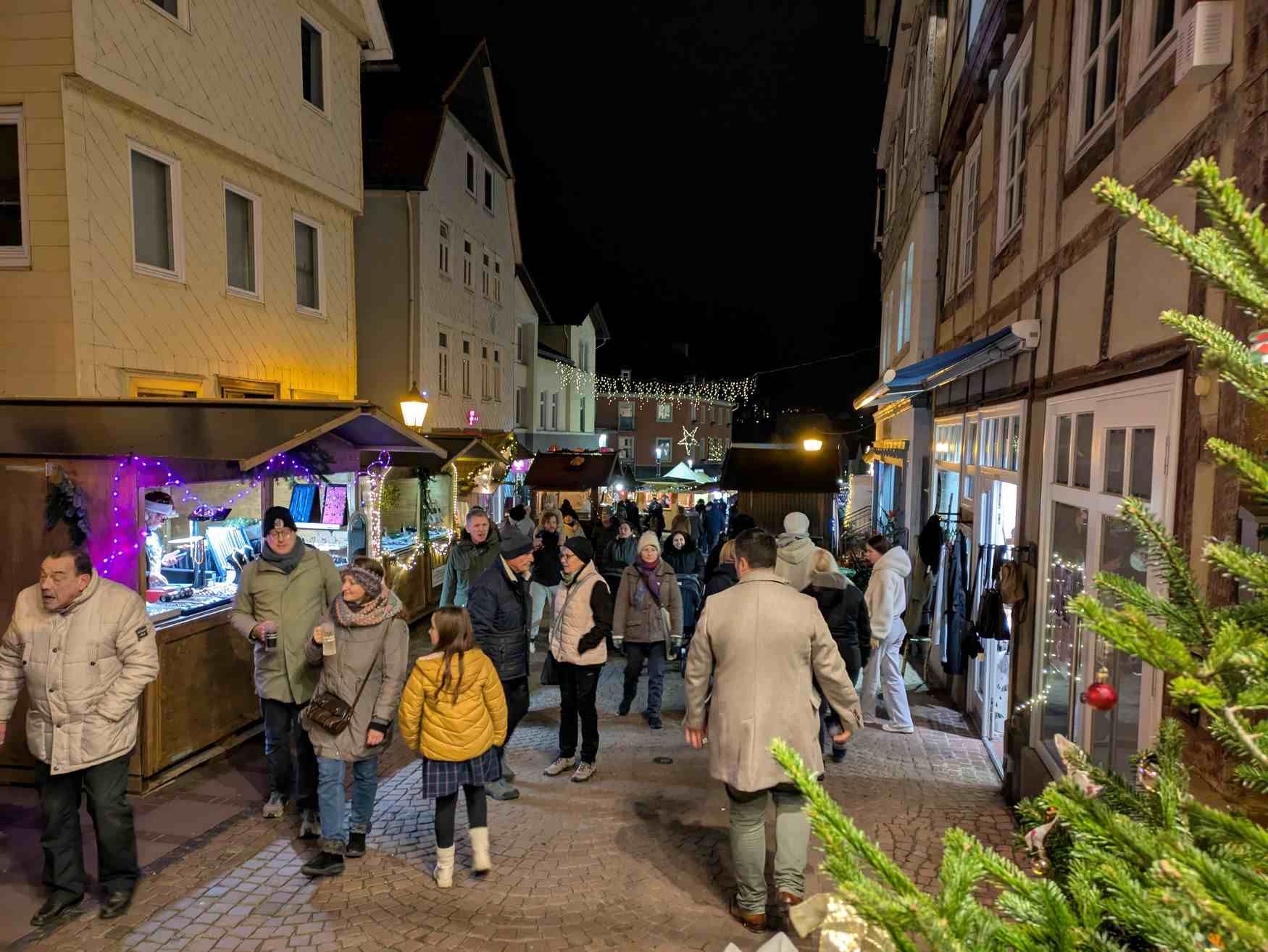 Zu sehen sind Menschen auf den Weihnachtsmarkt in der Brunnenstraße. Rechts und links an den Fachwerkhäusern stehen Stände.