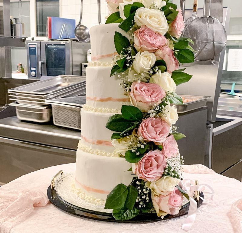 Vierstöckige Hochzeitstorte mit eleganter Rosendekoration – kunstvoll gestaltetes Highlight für eine romantische Hochzeitsfeier.