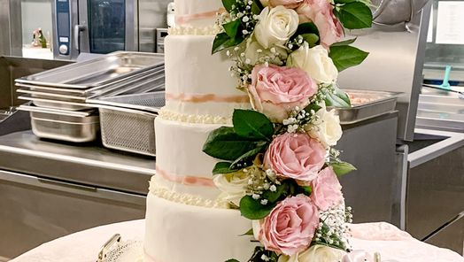 Vierstöckige Hochzeitstorte mit eleganter Rosendekoration – kunstvoll gestaltetes Highlight für eine romantische Hochzeitsfeier.