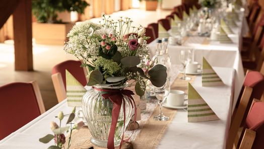 Festlich gedeckter Tisch mit einem eleganten Blumenarrangement im Zentrum – stilvolle Dekoration für Feiern, Hochzeiten oder besondere Anlässe.