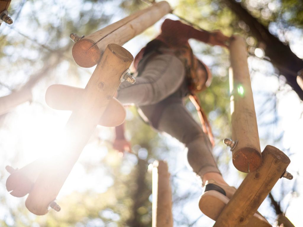 Eine Frau beim Klettern in einem Abenteuerpark -actionreiche Aktivität für inmitten Natur.
