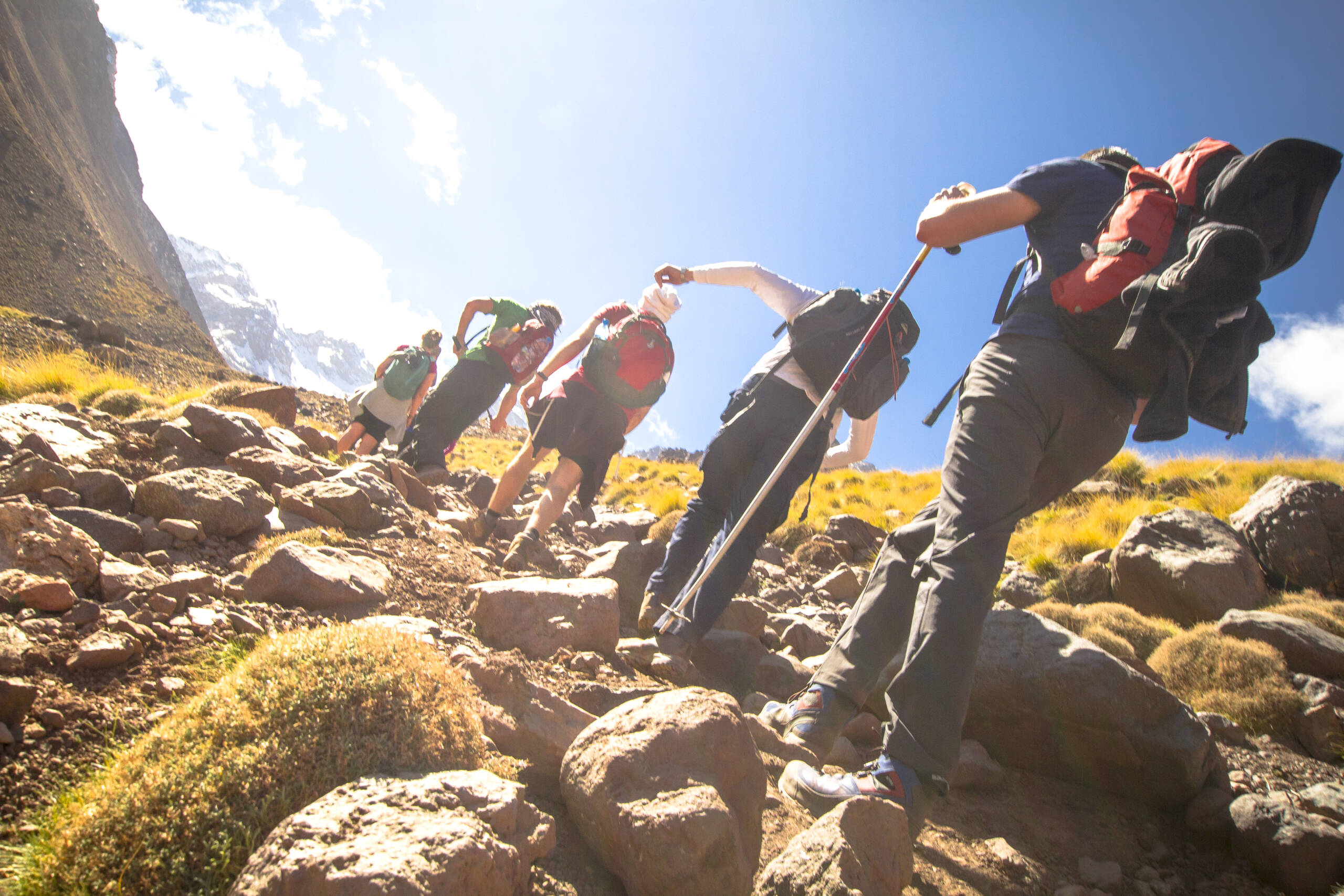 Personen beim Wandern in den Bergen aus der Froschperspektive, mit Blick in den Himmel – beeindruckendes Naturerlebnis und Aktivurlaub in alpiner Landschaft.
