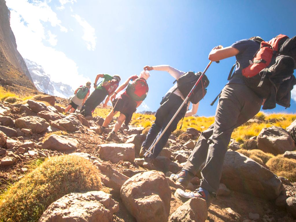 Personen beim Wandern in den Bergen aus der Froschperspektive, mit Blick in den Himmel – beeindruckendes Naturerlebnis und Aktivurlaub in alpiner Landschaft.