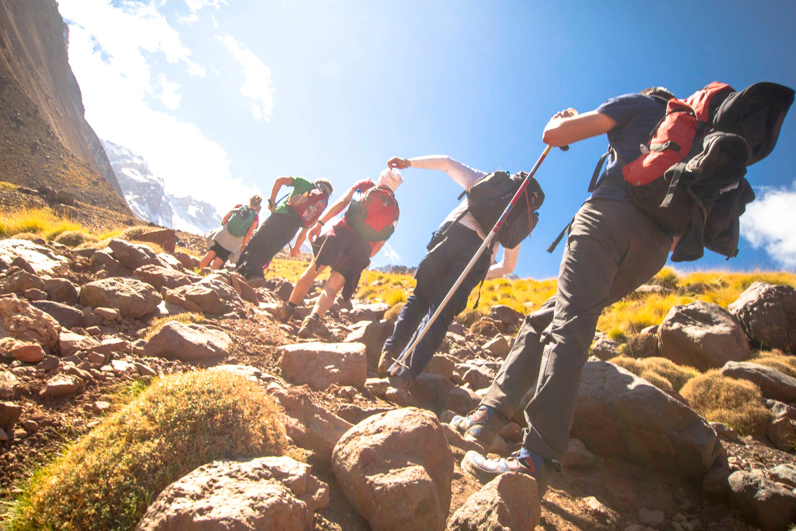 Personen beim Wandern in den Bergen aus der Froschperspektive, mit Blick in den Himmel – beeindruckendes Naturerlebnis und Aktivurlaub in alpiner Landschaft.