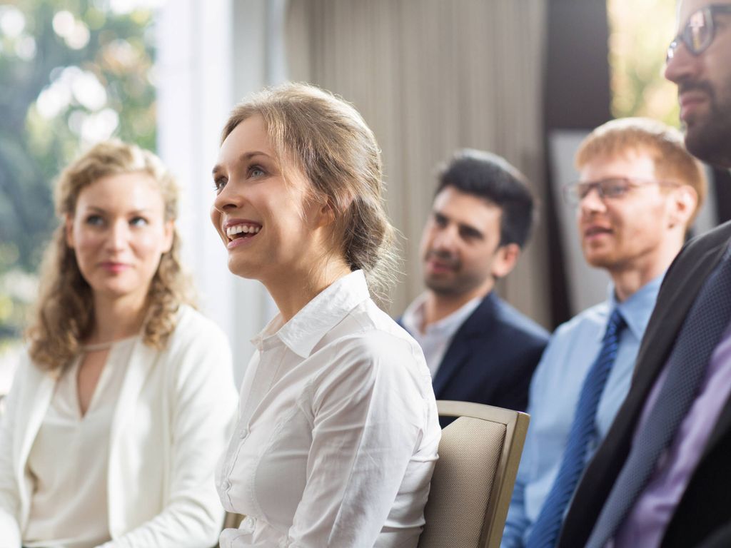 Lächelnde Frau sitzt bei einem Business-Meeting – professionelle und positive Arbeitsatmosphäre im Team.