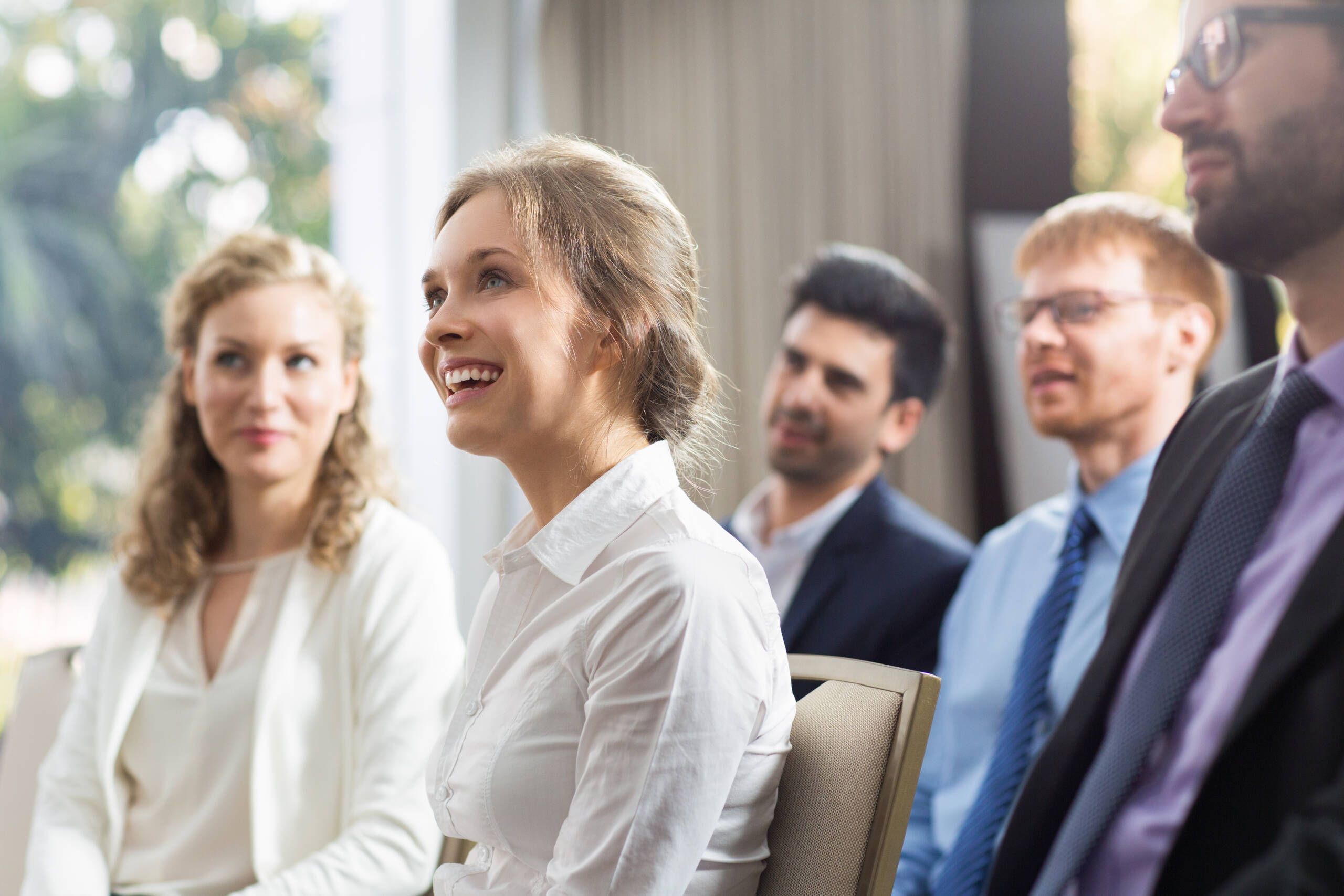 Lächelnde Frau sitzt bei einem Business-Meeting – professionelle und positive Arbeitsatmosphäre im Team.