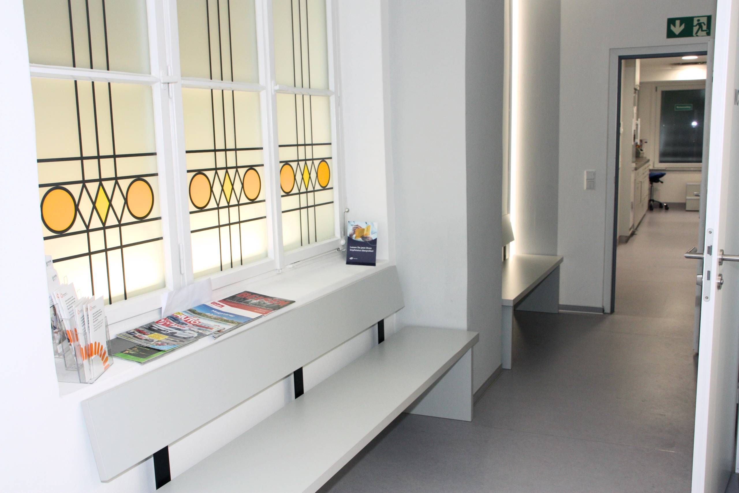 Praxisflur mit bunt verglastem Fenster, Bänke
