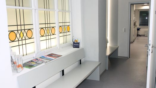 Praxisflur mit bunt verglastem Fenster, Bänke