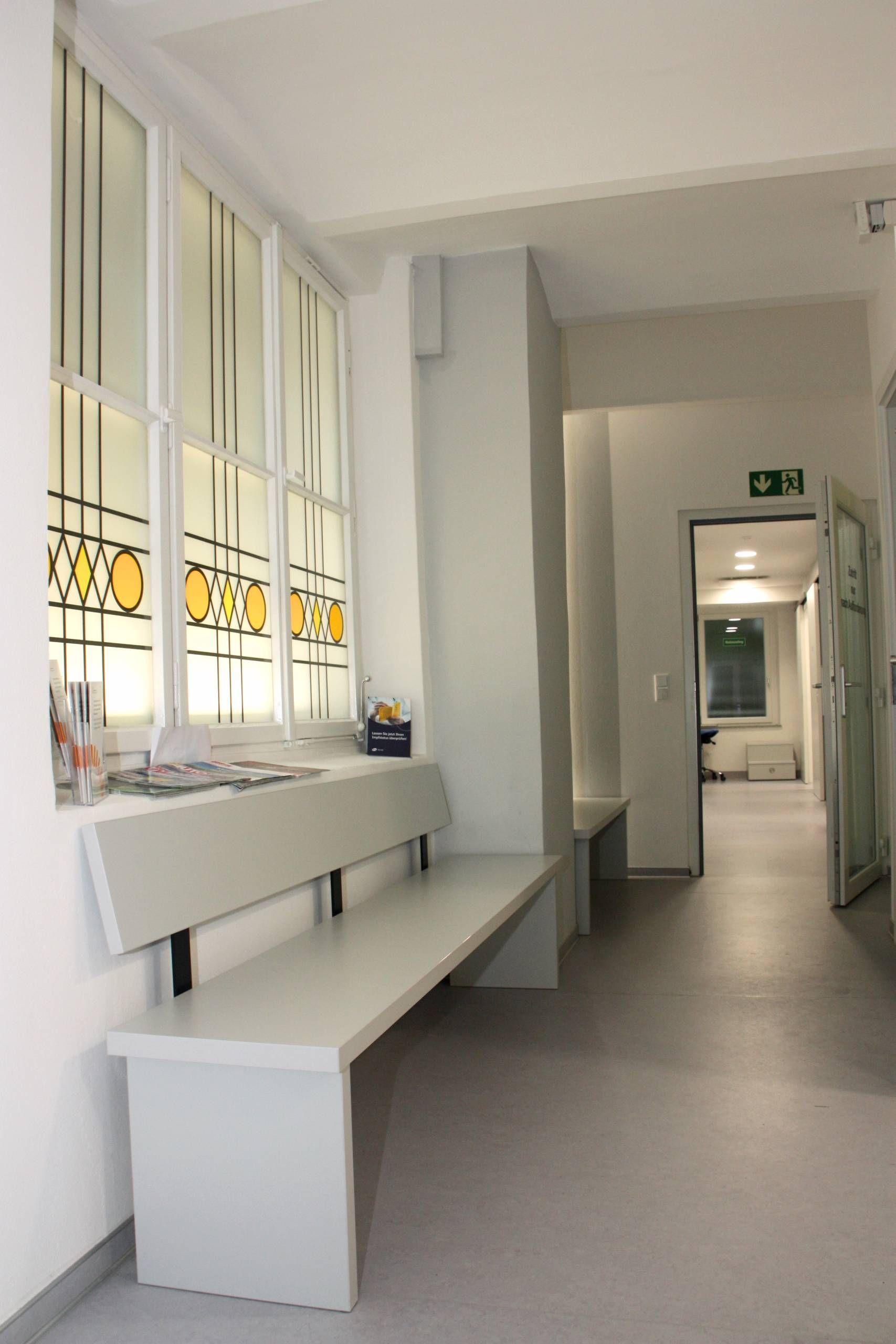 Praxisflur mit Sitzbank und bunt verglastem Fenster