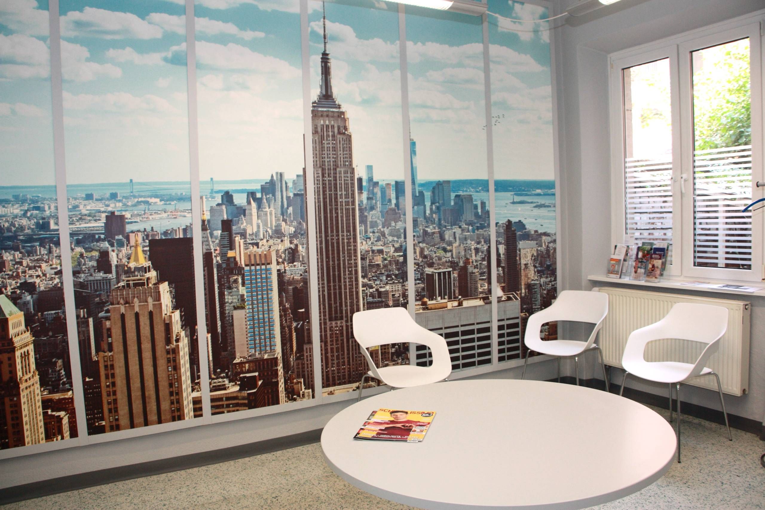 Wartezimmer mit großformatiger New York Fotowand, runder Tisch und drei Stühle