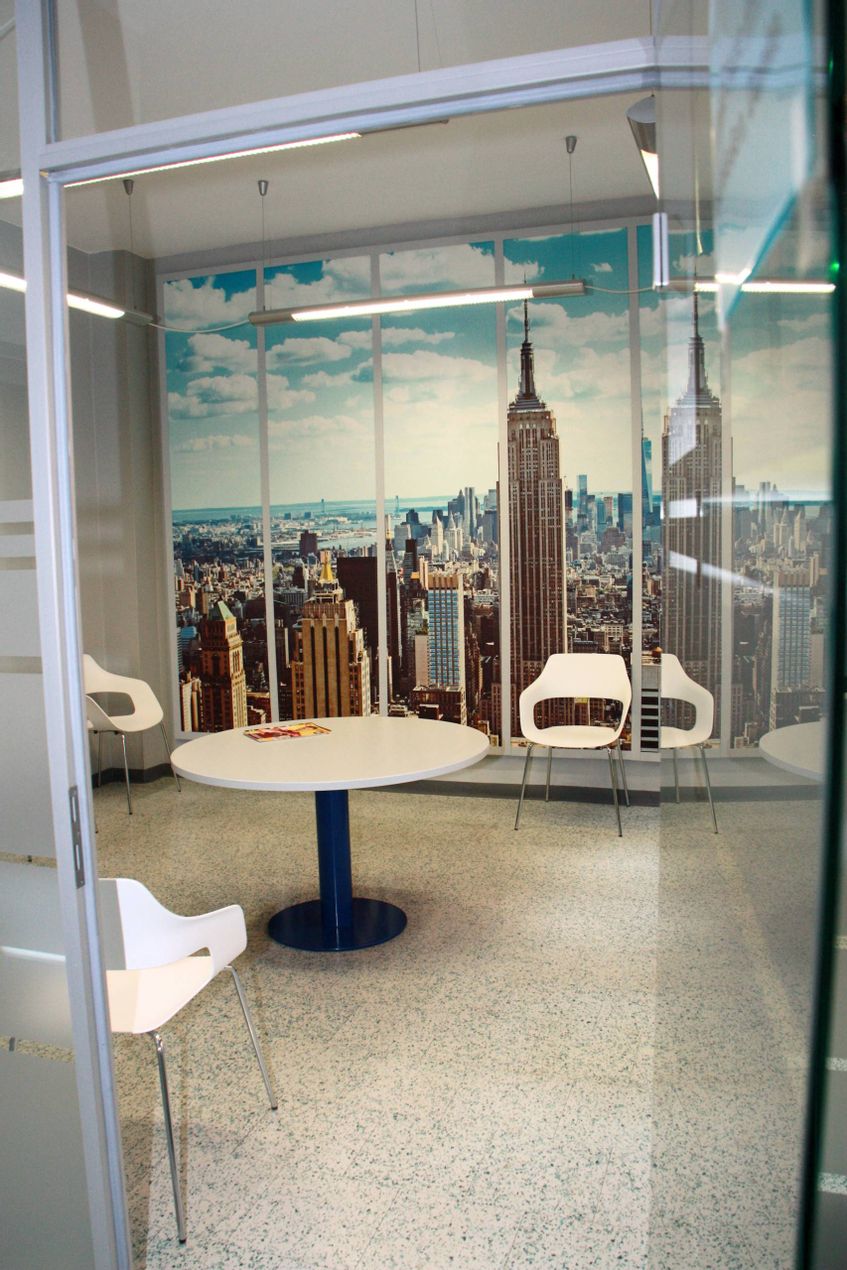 Wartezimmer mit großformatiger New York Fotowand, runder Tisch und drei Stühle