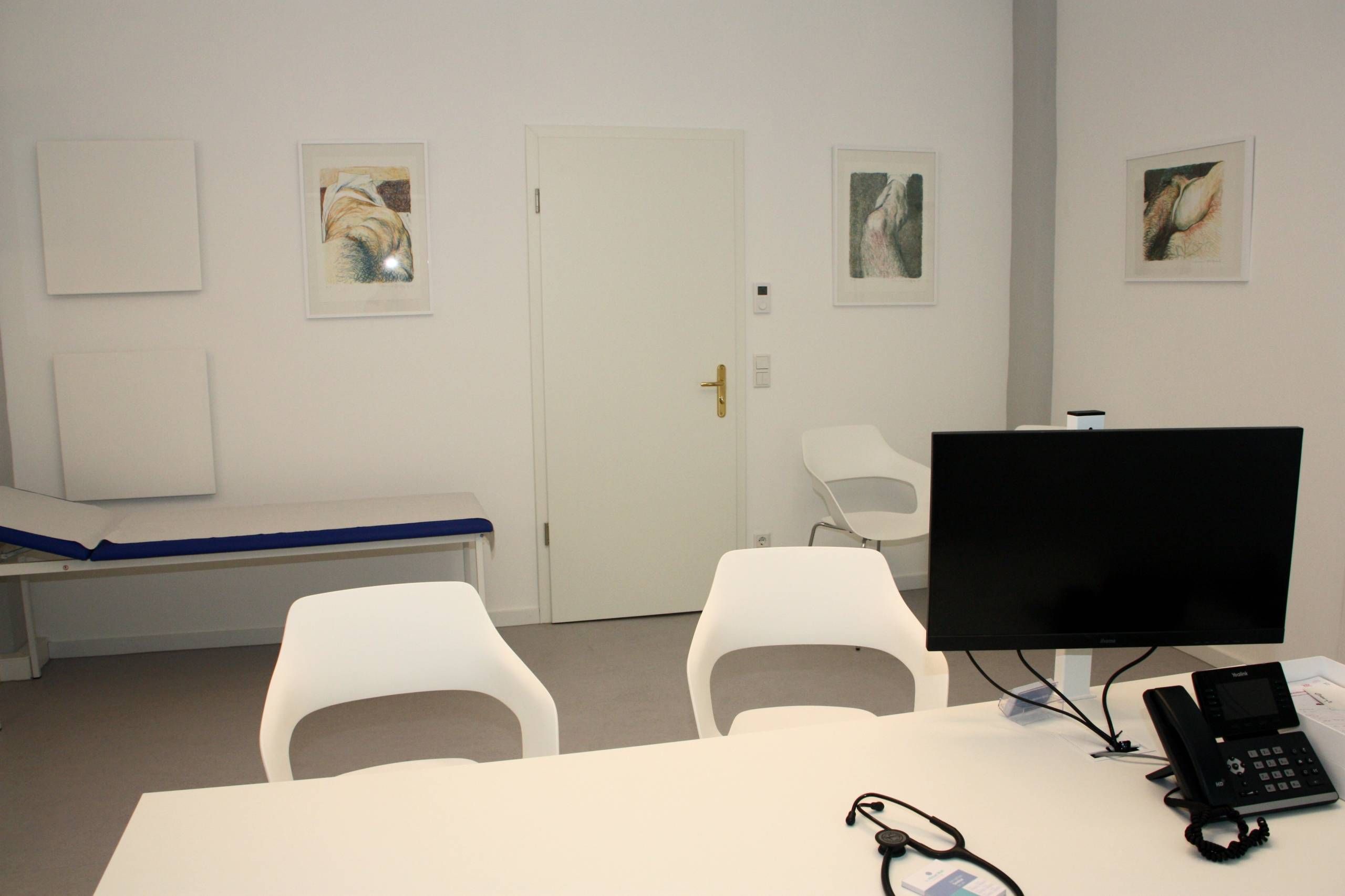 Sprechzimmer mit Tisch, Monitor und Telefon, drei Stühle