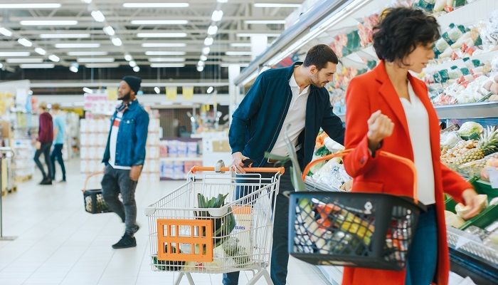 Menschen im Supermarkt suchen Lebensmittel, um anschließend B2C-Kundenfeedback abzugeben.