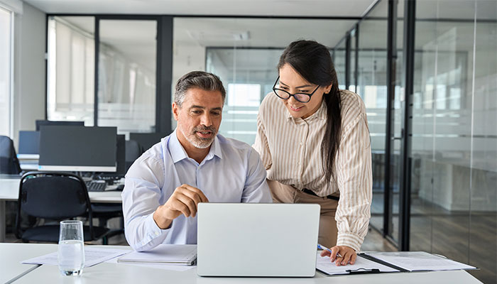 Zwei Personen diskutieren an einem Laptop über die Befragungssoftware.