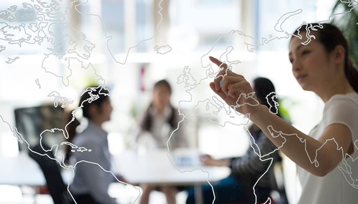 Eine Frau zeigt auf einer gläsernen Weltkarte das Land, welches für die Internationales Kundenfeedback ausgewählt wurde.