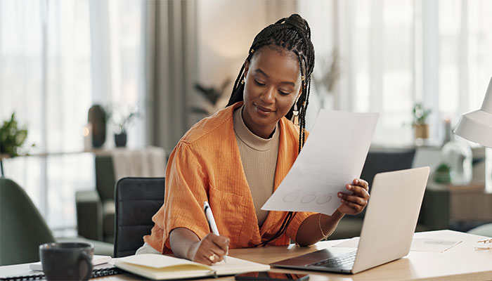 Eine Frau sitzt im Homeoffice und notiert die Ergebnisse der Statistiken der Panelsoftware.