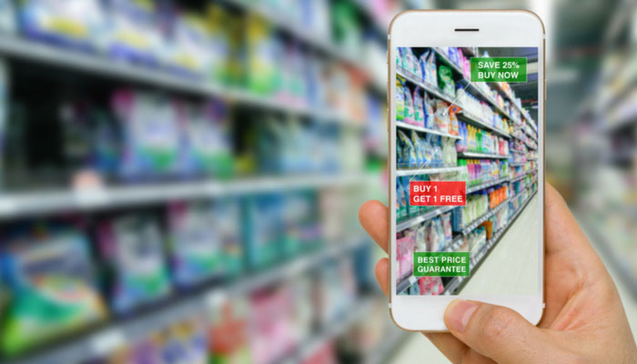 Preisanalysen zur Ermittlung des optimale Preises: Ein Mann scannt mit einem Handy Angebote in einem Supermarkt-Regal.