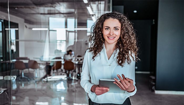 Eine Führungskraft ist im Büro mit einem Tablet in der Hand.