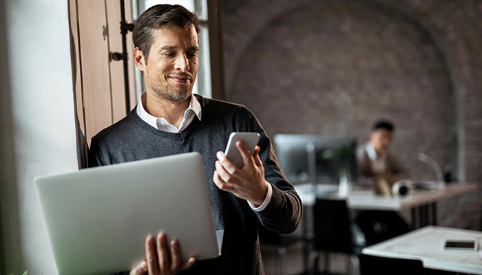 Panel-Studien mit qualitativen Formaten verbinden. Ein Mann hält einen Laptop und ein Handy in seinen Händen.