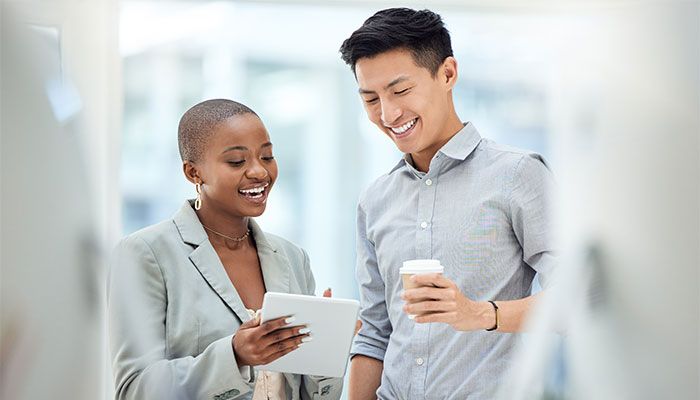 Zwei Kollegen sehen sich auf einem Tablet die positiven Ergebnisse des Puls-Checks an.
