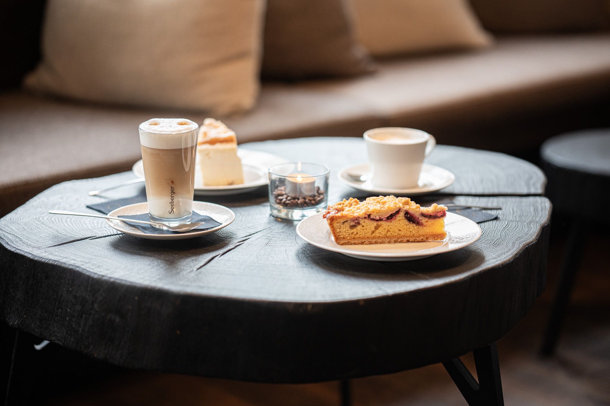 Ein gedeckter Tisch mit zwei angerichteten Kuchenstücken und zwei Kaffeespezialitäten – ein einladender Moment zum Genießen in der Speisegalerie Fischen.
