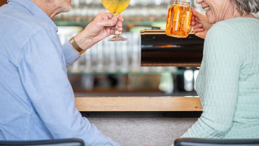 Seniorenpaar sitzt an der Bar der Speisegalerie und genießt ein leckeres Getränk in gemütlicher Atmosphäre.